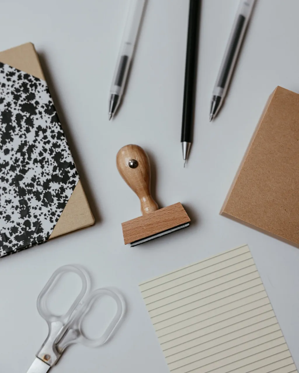 Pens, wooden stamp, notebook, lined paper and scissors on a desk — stationery and office supplies for wholesalers selling B2B with their VentasxMayor store